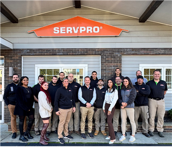 Our team poses in front of a wall decorated with SERVPRO-inspired street art in our warehouse